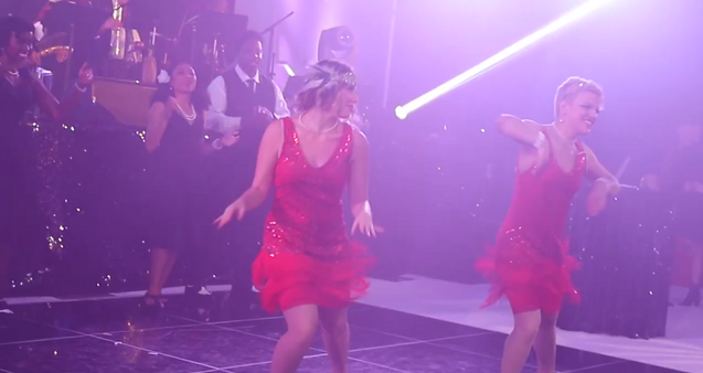 Two individuals in red dresses dancing on a stage in the jazz show