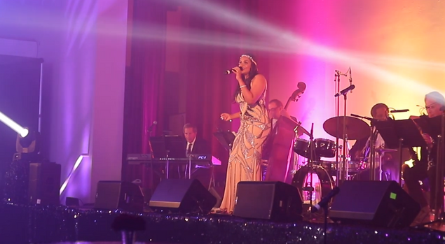 Female jazz vocalist in elegant white dress, holding microphone.